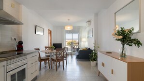 A modern kitchen with a dining area, a sofa, and a potted plant.