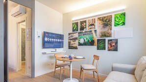 Un salon moderne avec une table à manger ronde, deux chaises, un canapé et un téléviseur à écran plat fixé au mur.