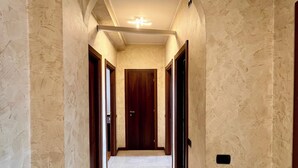 A hallway with a marble floor, wooden doors, and a ceiling light fixture. - Spacious Living with Balcony near Fondazione P... (Milan)