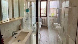 A modern bathroom with a glass shower enclosure, a sink with a mirror, and a toilet. - Spacious Living with Balcony near Fondazione P... (Milan)