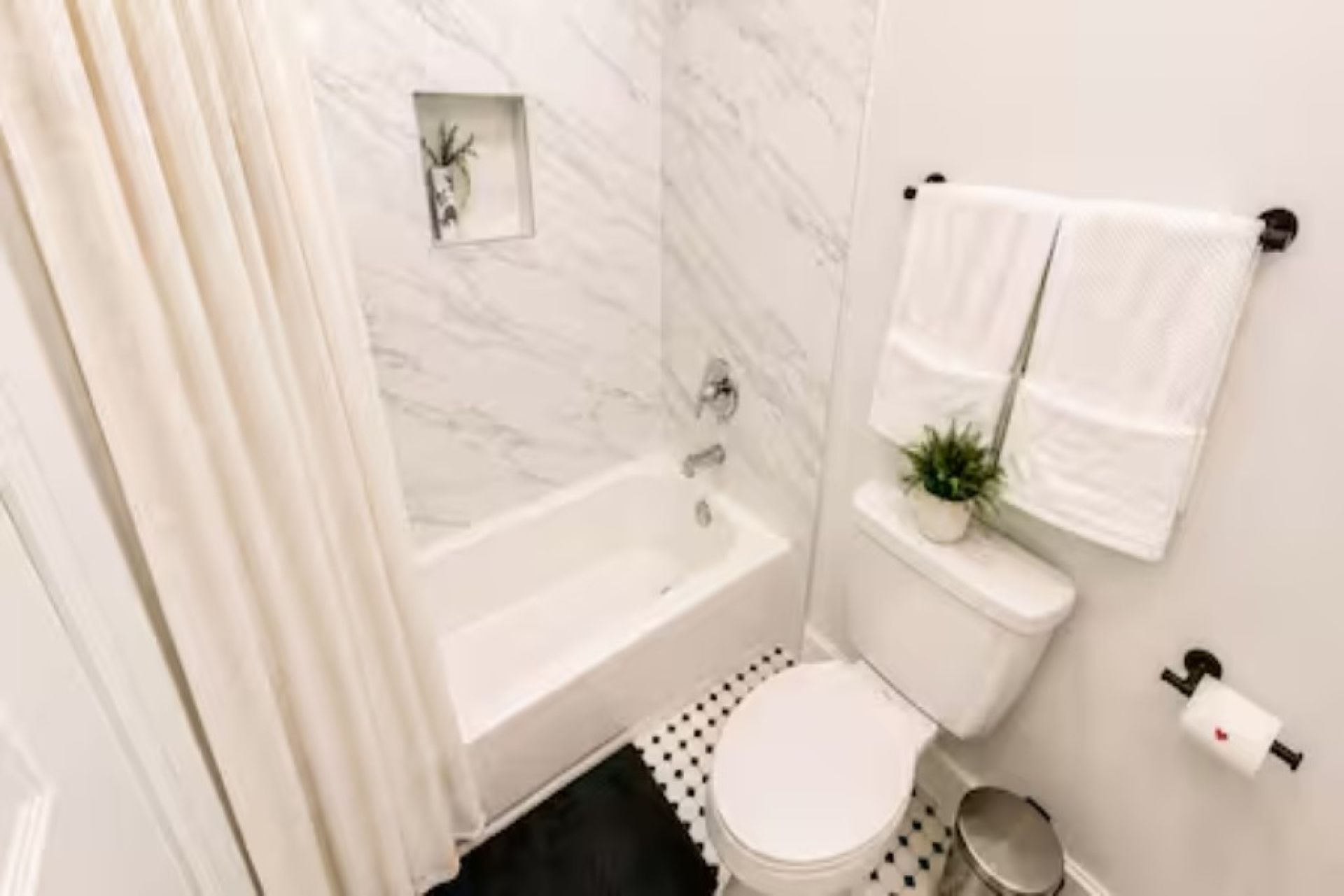 Une salle de bain avec une baignoire, des toilettes et une petite plante en pot.