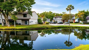 A residential area with houses, a pond reflecting the buildings, and parked cars. - Lakefront |Long Term Friendly |Pets|Cozy Fireplace (Jacksonville)