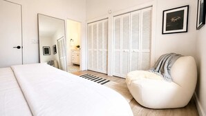 A bedroom with a bed, a chair, a wardrobe, and a mirror. - Lakefront |Long Term Friendly |Pets|Cozy Fireplace (Jacksonville)