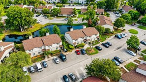 Luchtbeeld van een woonwijk met huizen, een parkeerplaats en een klein vijver.