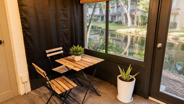 A corner with a wooden table and chairs, a potted plant, and a view of a residential area through a glass door. - Lakefront |Long Term Friendly |Pets|Cozy Fireplace (Jacksonville)