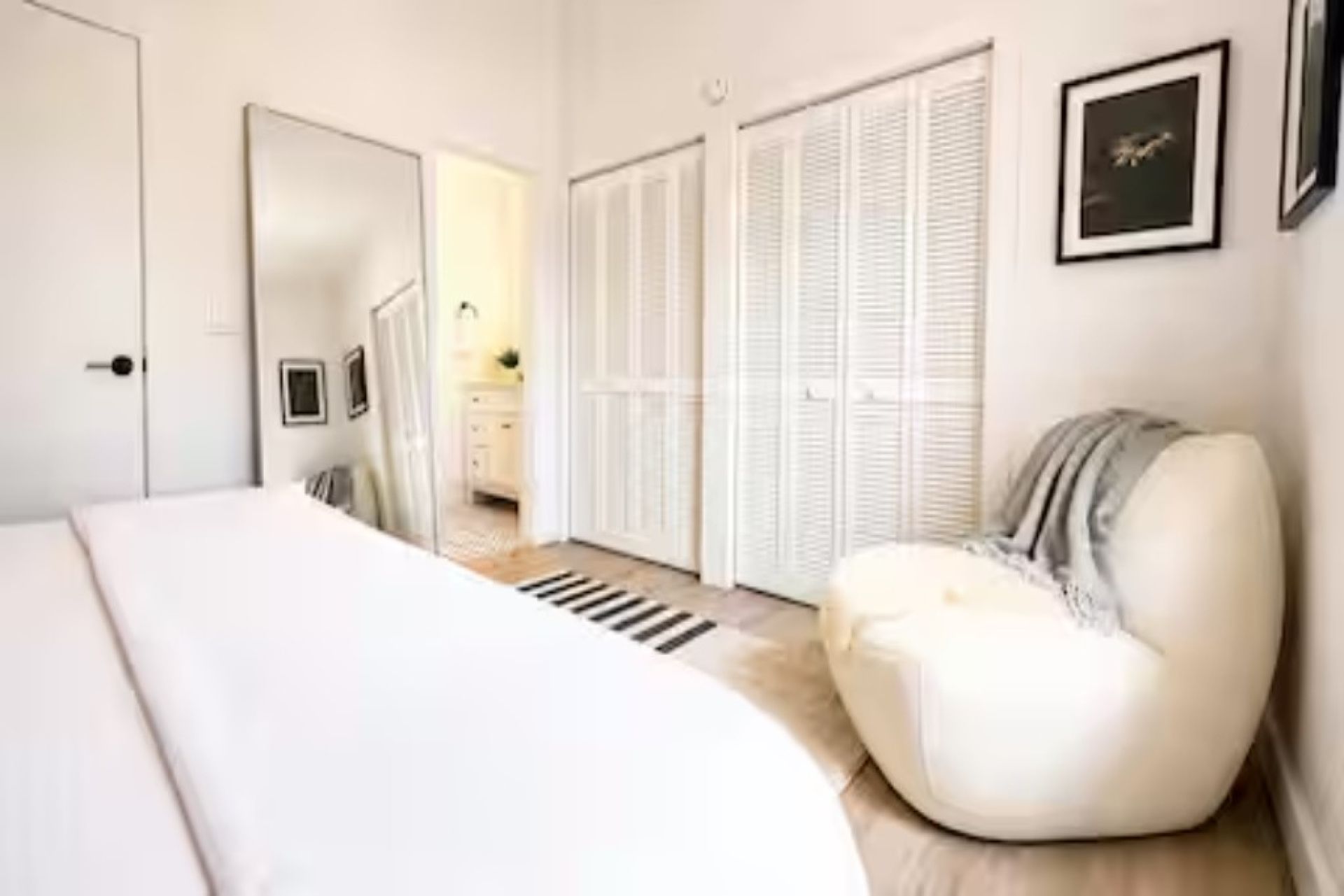 Una camera da letto con un letto, una sedia, un armadio e uno specchio.