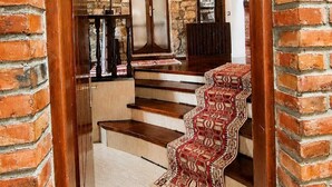 A staircase with a patterned carpet, a wooden door, and a stone wall. - Guva Stone House Mangalem (Berat)