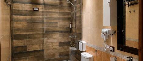 Une salle de bain avec une douche, deux toilettes, un lavabo et un miroir.