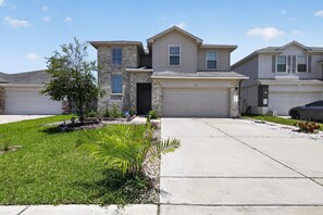 A residential house with a garage, a driveway, and a well-maintained lawn. - Spacious Retreat | Pool Table, Firepit + Backyard (Houston)