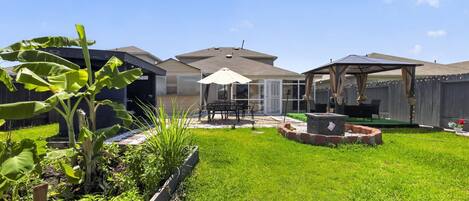 A backyard with a patio, a covered seating area, and a fire pit.