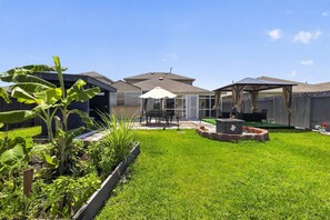 A backyard with a patio, a covered seating area, and a fire pit. - Spacious Retreat | Pool Table, Firepit + Backyard (Houston)