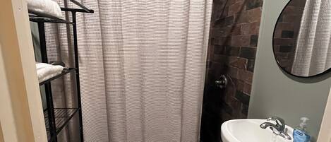Une salle de bain équipée de toilettes, d’un lavabo, d’un rideau de douche et d’un miroir.
