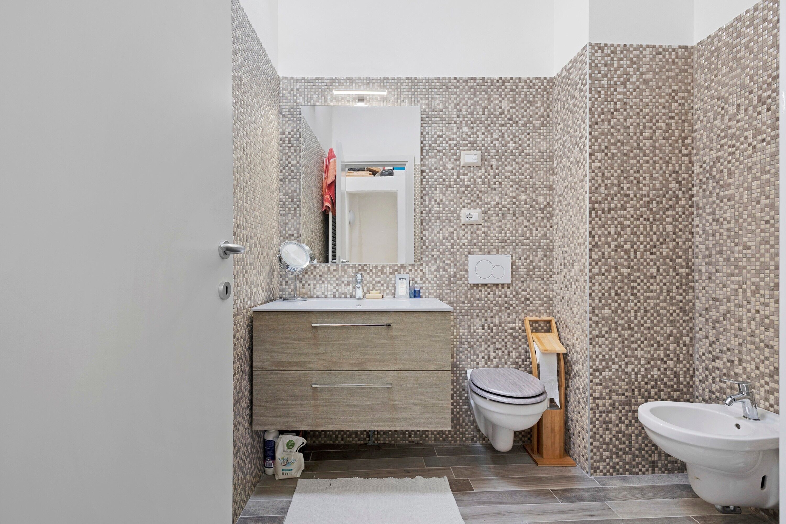 Une salle de bain moderne avec un mur carrelé, un lavabo, des toilettes et un bidet.