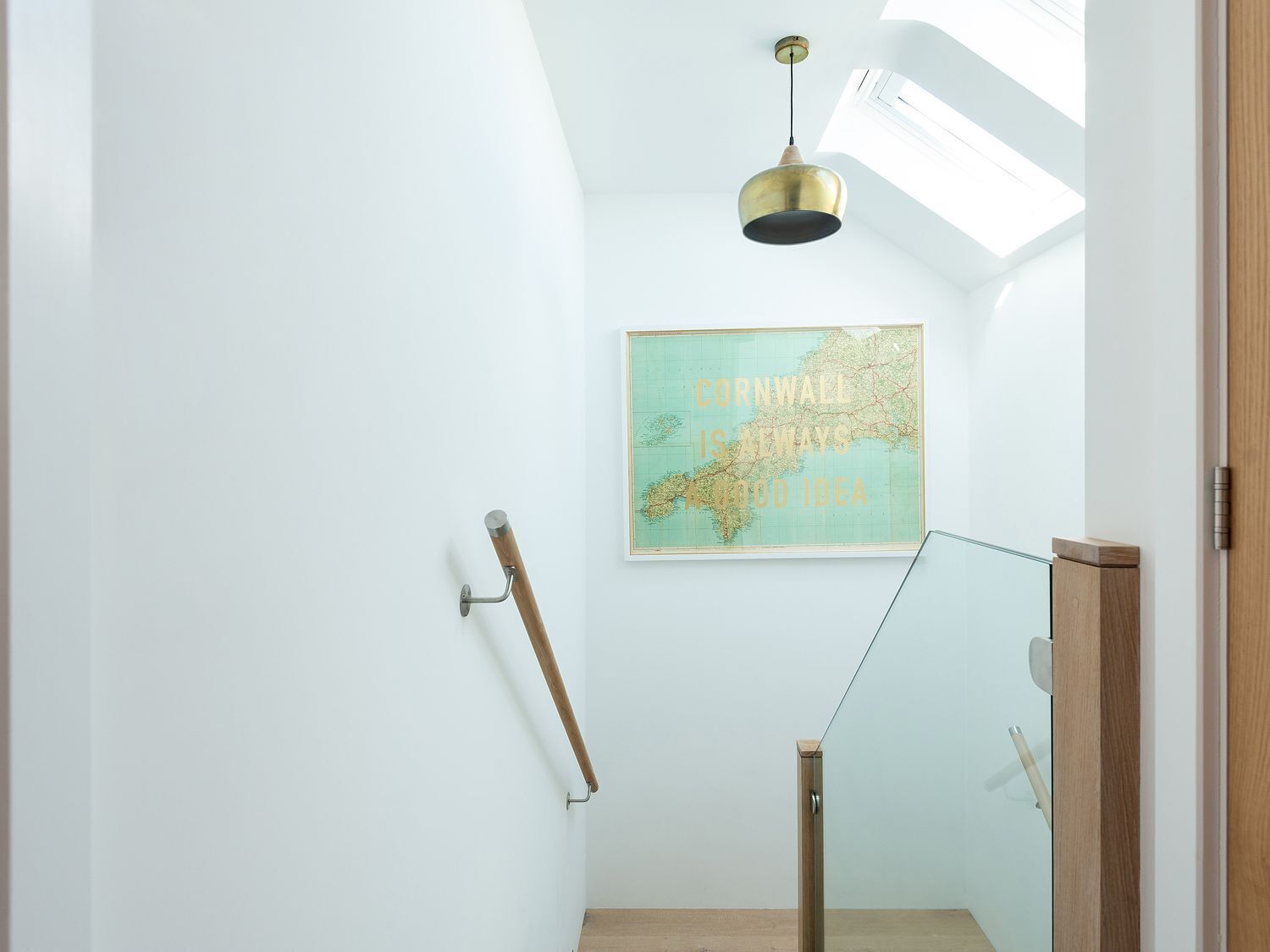 A modern interior with a skylight, a map on the wall, and a wooden handrail.