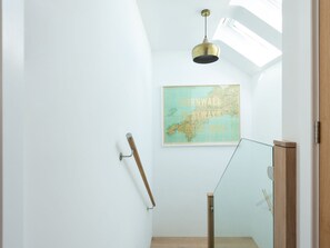 A modern interior with a skylight, a map on the wall, and a wooden handrail.