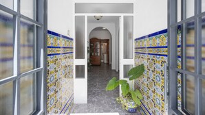 A hallway with patterned tiles, a potted plant, and a wooden cabinet. - Holiday Home 'En La Gloria' – Accessible, Central Location Near the Beach (Barbate)