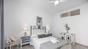 A bedroom with a bed, bedside tables, a chair, a dresser, and a ceiling fan. - Holiday Home 'En La Gloria' – Accessible, Central Location Near the Beach (Barbate)