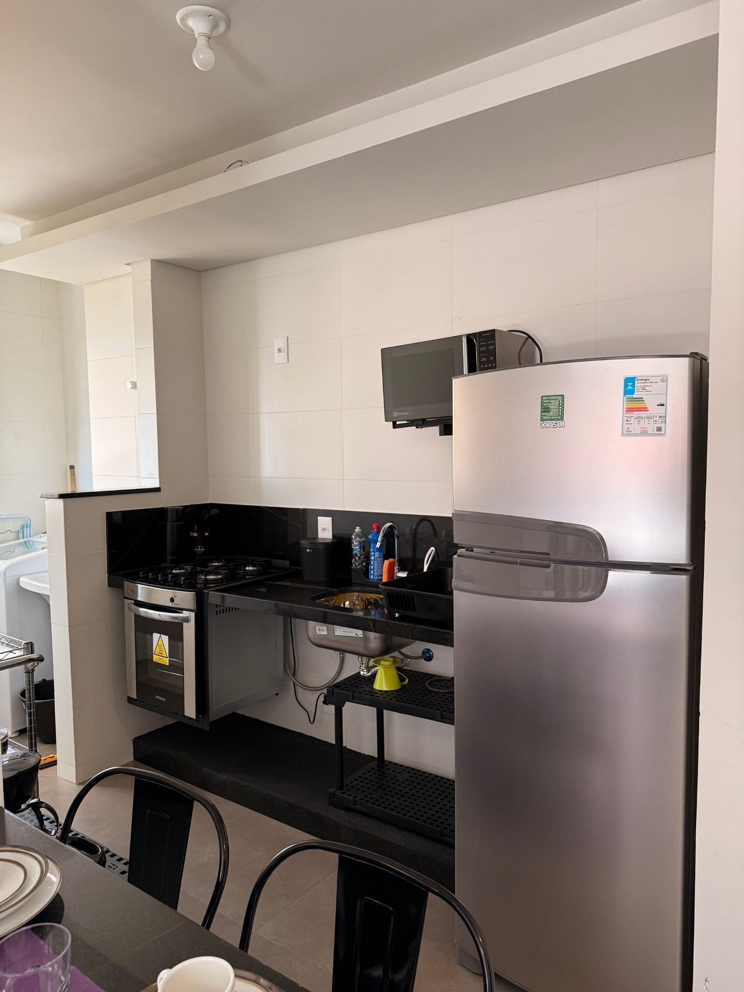 A modern kitchen with a stainless steel refrigerator, a microwave, a stove, and a sink.