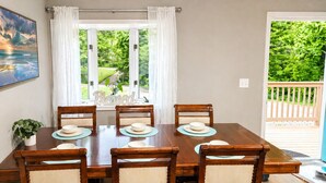 Un comedor con una mesa de madera, seis sillas y vistas a la vegetación a través de un ventanal.