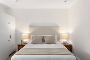 A bedroom with a bed, bedside lamps, a nightstand, a wardrobe, and a wall-mounted light fixture. - The Surry Studio Cosy Stay near Cafs and Nightlife (Surry Hills)