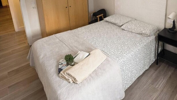 Ein Schlafzimmer mit Bett, Kleiderschrank, Nachttisch und Lampe.