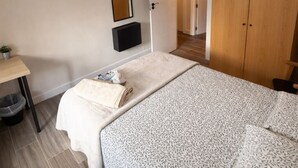 Ein Schlafzimmer mit einem Bett, einem Nachttisch, einem Spiegel, einem Kleiderschrank und einer Tür zu einem anderen Raum.