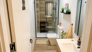 Ein modernes Badezimmer mit Duschkabine aus Glas, Toilette und Waschbecken mit Spiegel.