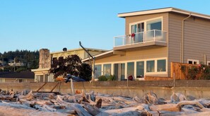 A modern two-story house with a balcony, large windows, and a satellite dish. - Enjoy Camano Tidalwilds waterfront beach house w/ hot tub, sups, kayak and more! (Camano)