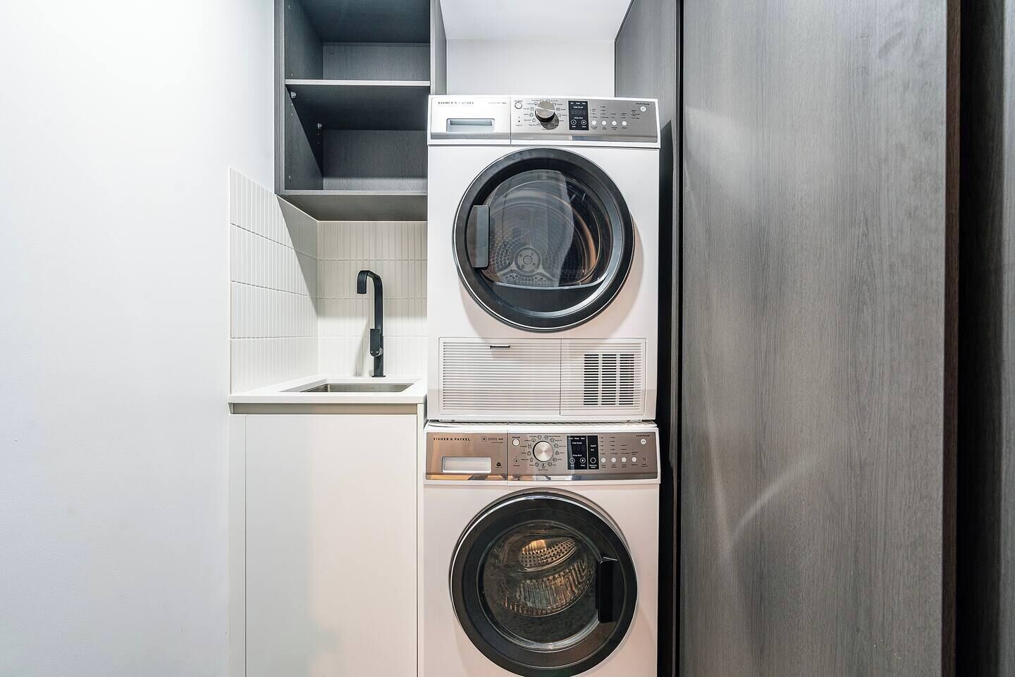A compact laundry area with a washing machine, dryer, and a sink.