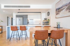 Eine moderne Küche mit Kochinsel, Barhocker und Esstisch.