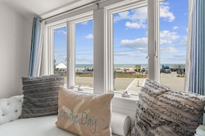 Una habitación con vistas a la playa, un sofá blanco y almohadas con vuelo.