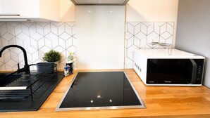 A modern kitchen with a Bosch induction cooktop, a Samsung microwave, and a black faucet.