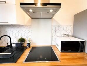 Een moderne keuken met een Bosch inductiekookplaat, een Samsung magnetron en een zwarte kraan.