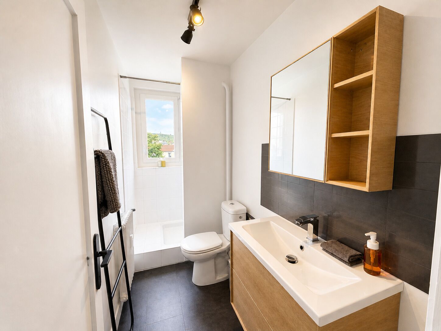 A modern bathroom with a bathtub, toilet, and a large mirror above the sink.