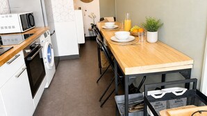 A compact kitchen with a wooden table, a washing machine, a microwave, and a sink.