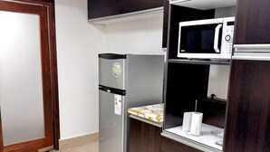 A compact kitchen with a refrigerator, microwave, and built-in oven.