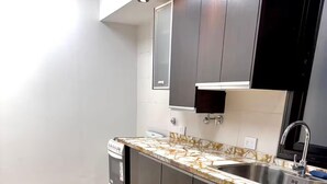 A modern kitchen with a marble countertop, stainless steel sink, and built-in cabinets.