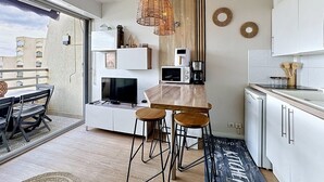 Moderni keittiö, jossa on puinen keittiösaareke, baarituolit, mikroaaltouuni ja kahvinkeitin.