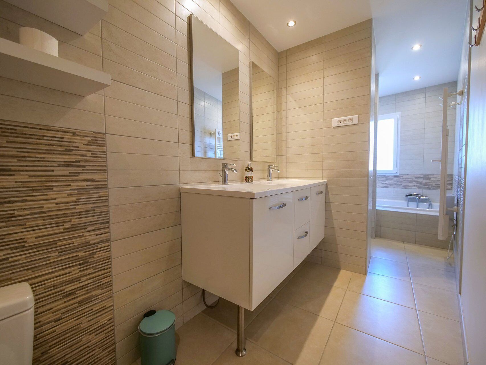A modern bathroom with a large mirror, a sink, and a shower area.