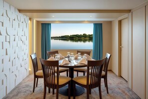 A dining area with a table set for six, a view of a lake, and a patterned wall.
