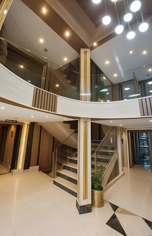 A modern interior with a curved staircase, glass railings, and recessed lighting.