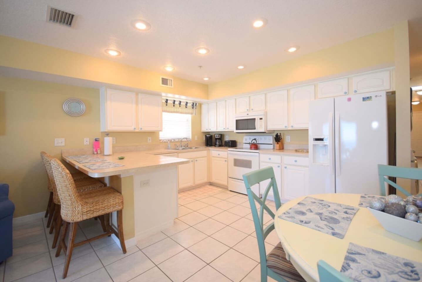 A compact kitchen with white cabinets, a central island, and a dining area with chairs.