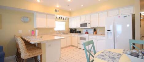A compact kitchen with white cabinets, a central island, and a dining area with chairs.