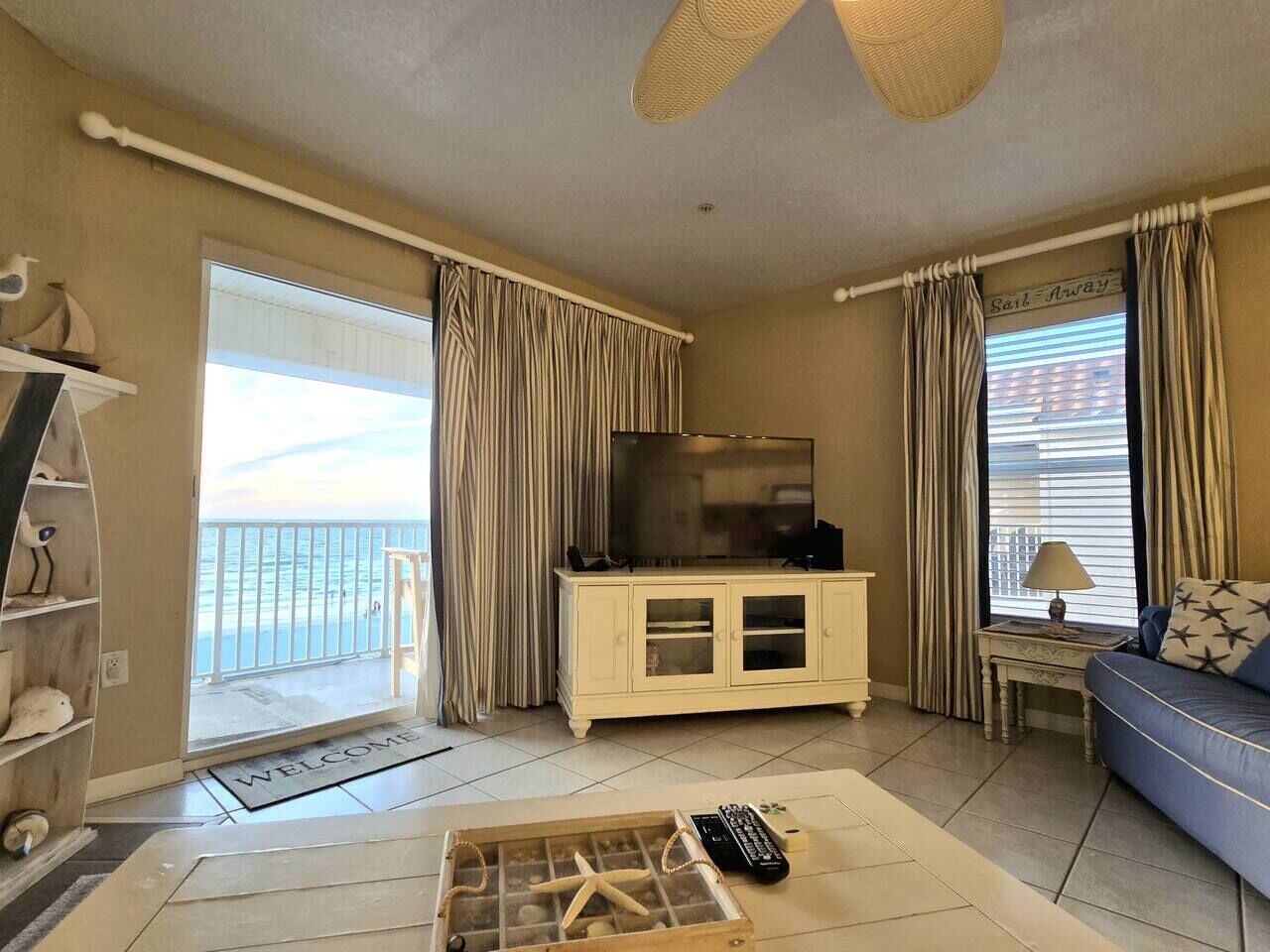A living room with a television, a sofa, a coffee table, and a balcony door.