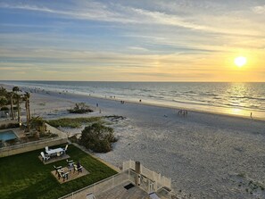 Blick auf einen Strand mit Poolbereich, Sitzgelegenheiten im Freien und einer Treppe zum Strand.