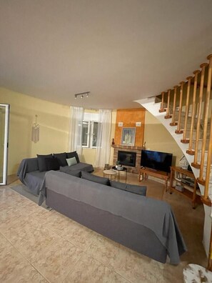 A living room with a sofa set, a television, and a staircase. - Soothing villa 300 metres from the beach (Les Tres Cales)
