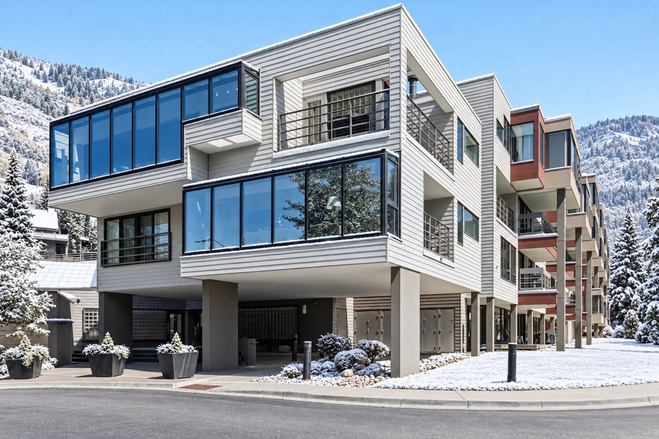 A modern multi-story building with large windows, a flat roof, and a snow-covered landscape.