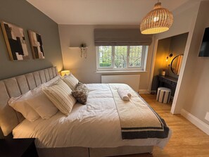 Ein Schlafzimmer mit Bett, Nachttischlampe, Fenster und einer Pendelleuchte.