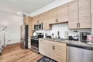 Una cocina moderna con armarios de madera, electrodomésticos de acero inoxidable y encimera de granito.