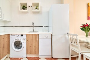 Eine kompakte Küche mit Waschmaschine, Geschirrspüler und Kühlschrank.